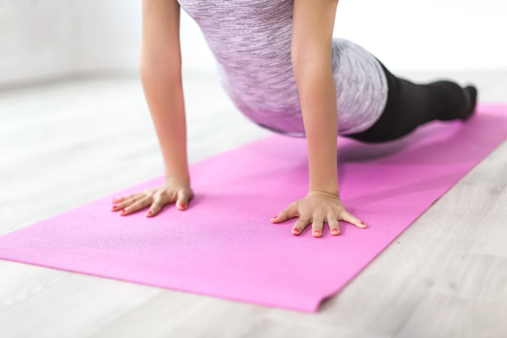 Woman practising yoga on a pink mat during a gym class at Gym Plus