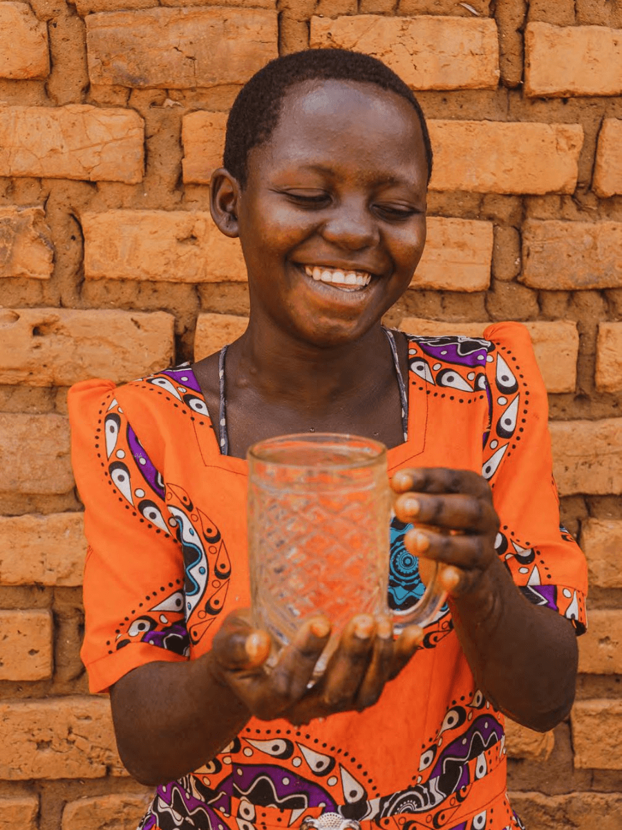 Girl in Uganda holding glass of clean drinking water