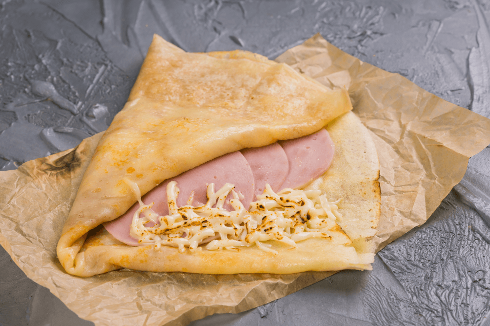 Savoury ham and cheese crêpe on parchment paper, a healthy Pancake Tuesday alternative from Gymplus.