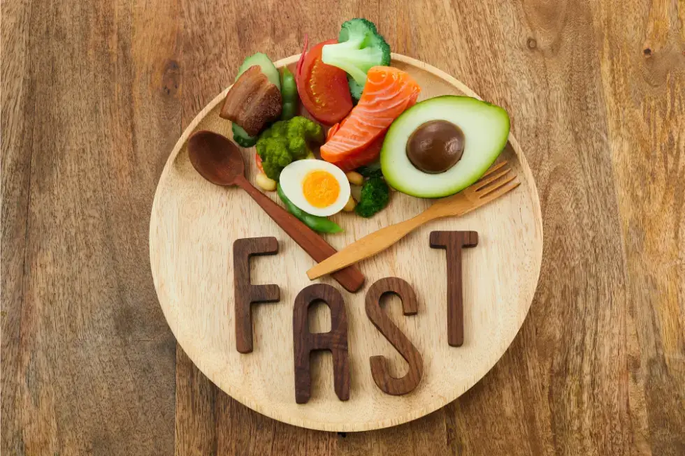 Healthy foods and the word FAST on a plate illustrating intermittent fasting benefits | Gym Plus