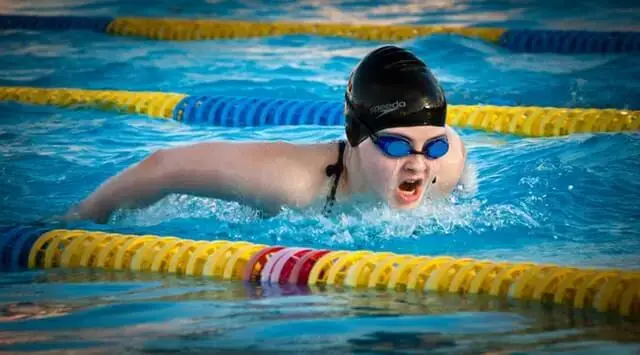 Adult swimmer practising butterfly stroke during a swimming lesson in an indoor pool at Gym Plus