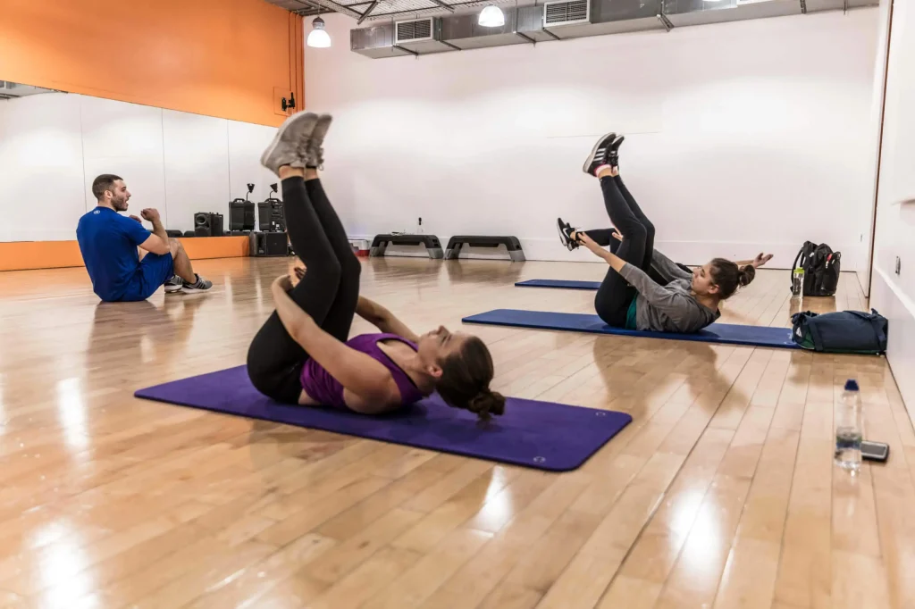 Pilates for beginners at Gym Plus, with members practising mat Pilates exercises during a group class.