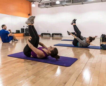 Pilates For Beginners At Gym Plus, With Members Practising Mat Pilates Exercises During A Group Class.