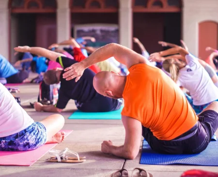 Yoga For Beginners At Gym Plus, With A Group Practising Yoga Poses On Mats During A Class.